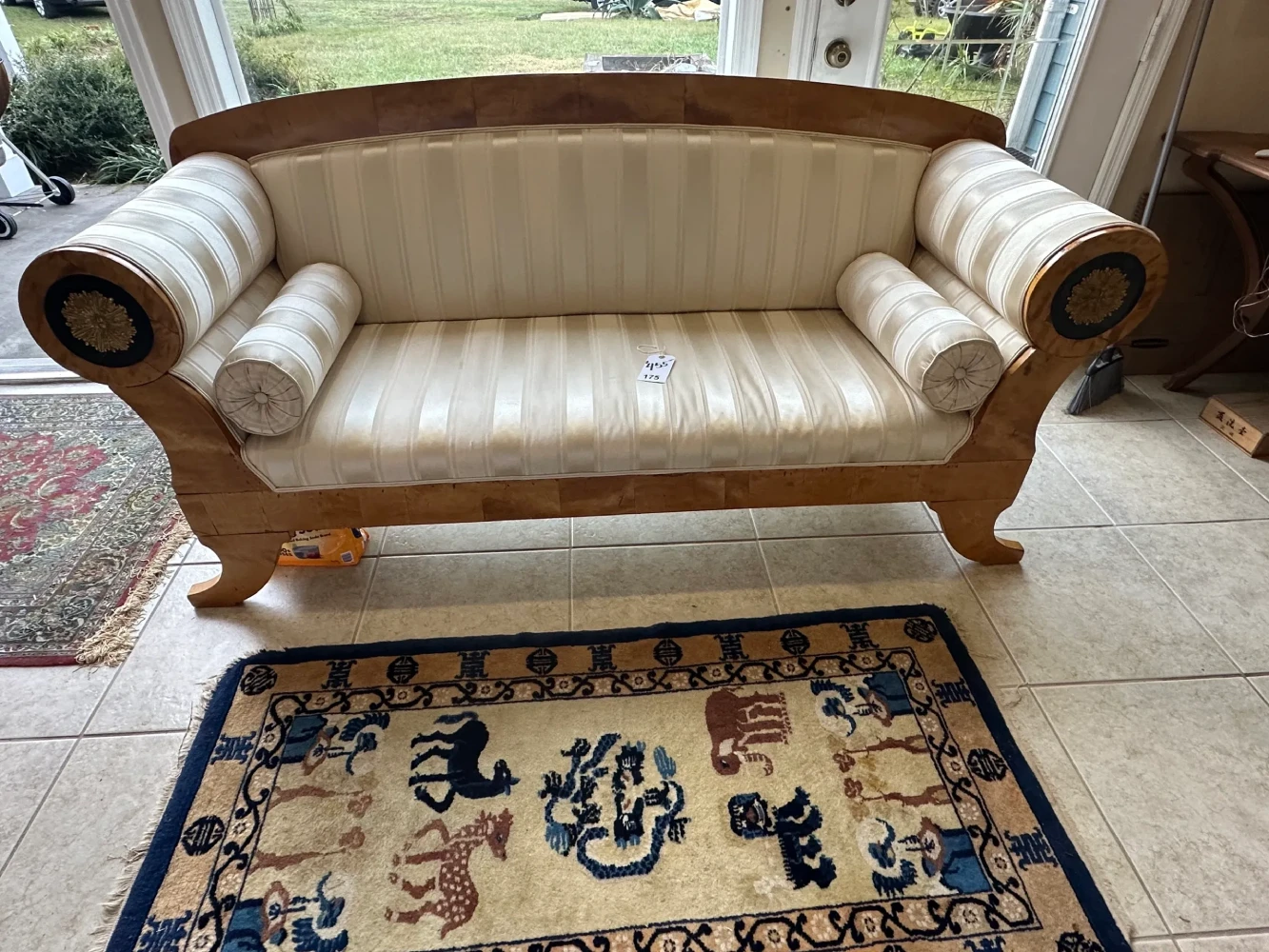 Statement sofa with cream tufted upholstery, exposed carved-wood frame, scroll arms, and decorative medallion details.