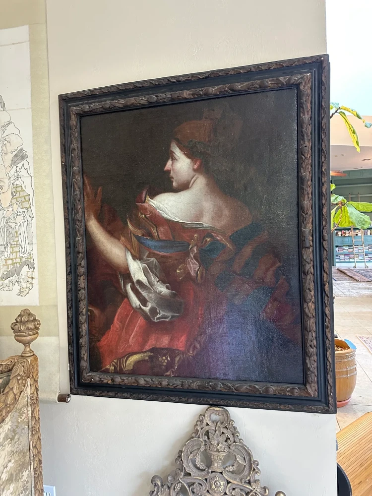 Large framed portrait of a woman in profile holding a small object against a dark background.