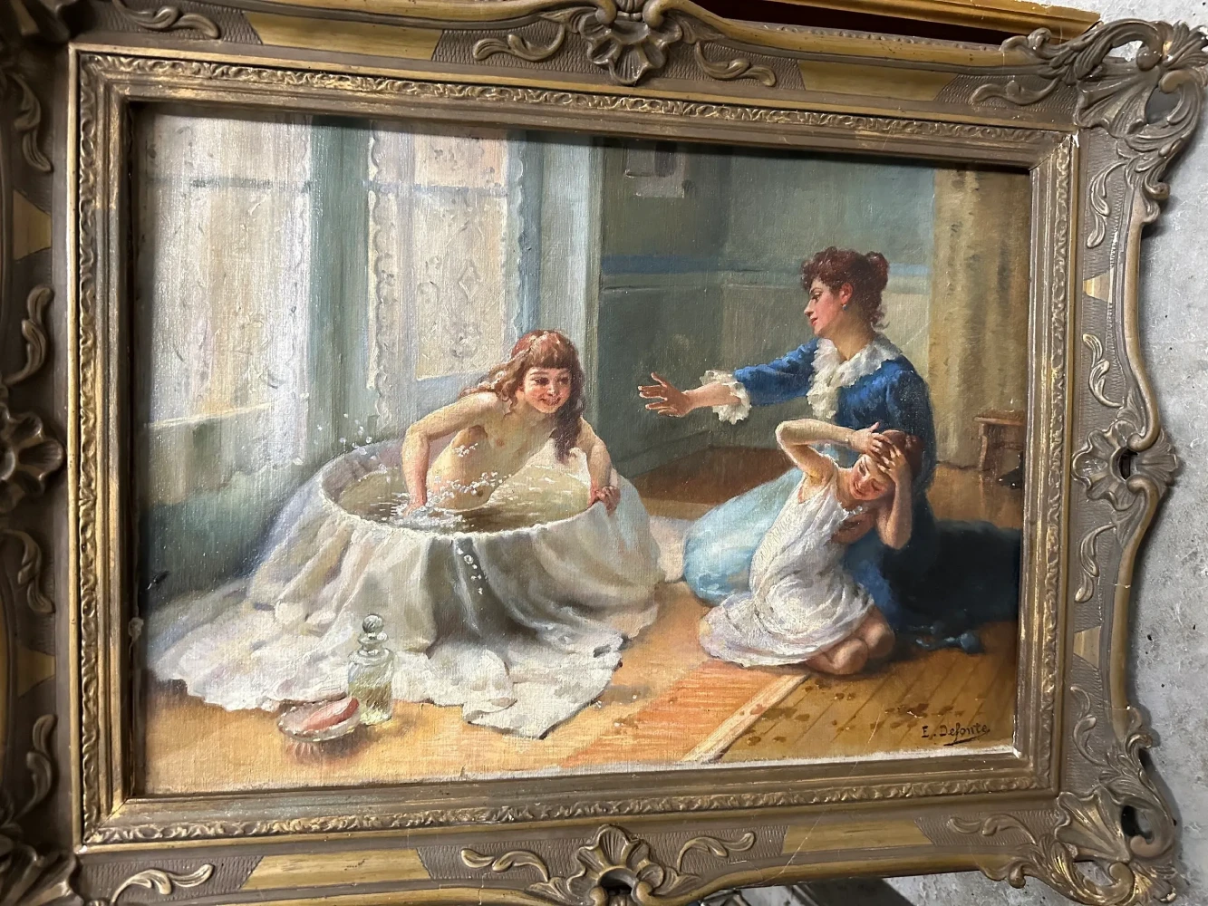 Ornately framed interior scene of two women in Victorian dress seated in conversation by a window.